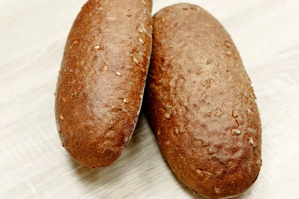 Dois pão cozido preto em um fundo de madeira leve — Fotografia de Stock