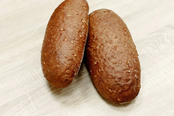 Δύο μαύρο ψωμί ψημένο σε ανοιχτόχρωμο φόντο ξύλινη — Φωτογραφία Αρχείου