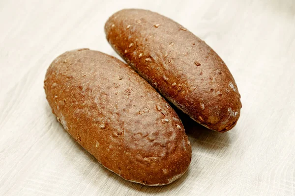 Dois pão cozido preto em um fundo de madeira leve — Fotografia de Stock