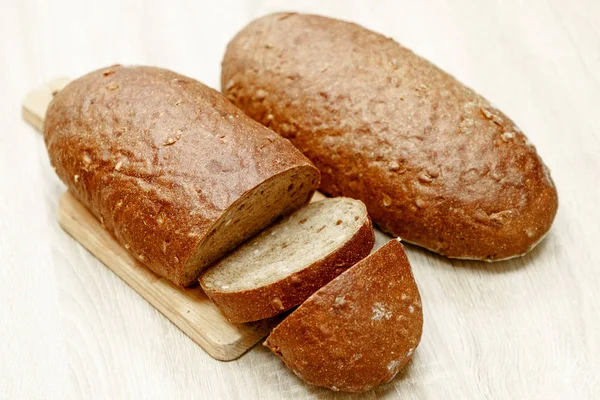 Δύο μαύρο ζυμωτό ψωμί, ένας από αυτούς είναι κομμένο σε φέτες — Φωτογραφία Αρχείου