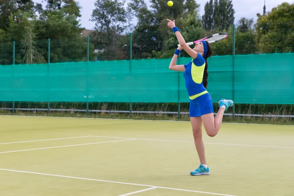 Mladá žena nosí sportovní oblečení slouží tenisový b s tenisem — Stock fotografie