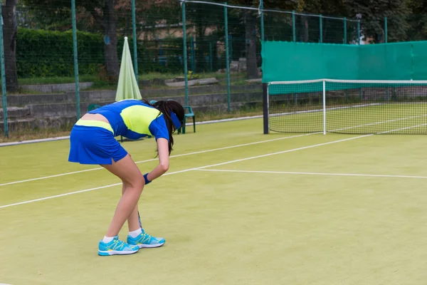 Junge Tennisspielerin bückte sich nach einem Ball — Stockfoto