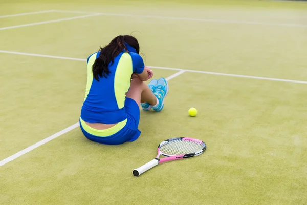 Расстроенная теннисистка сидит на корте — стоковое фото
