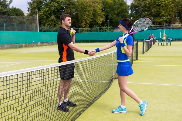 Un par de tenistas estrechando las manos sobre la red — Foto de Stock