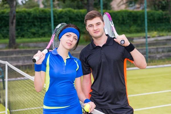 Pareja atlética de tenistas sosteniendo una raqueta y una pelota o — Foto de Stock