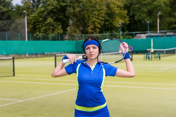 Joven mujer atractiva en ropa deportiva mantiene raqueta de tenis en su — Foto de Stock
