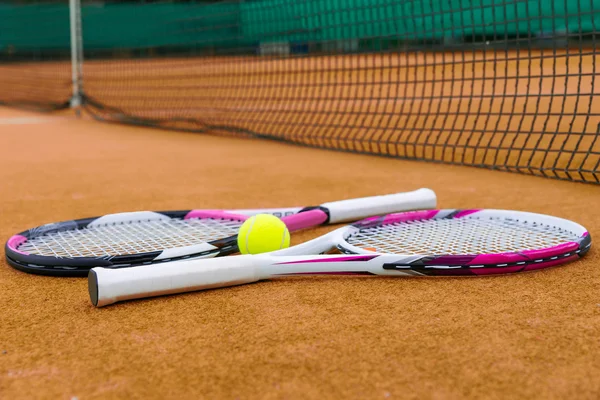 Sidovy på tennisracketar med en tennisboll på lera domstolen — Stockfoto