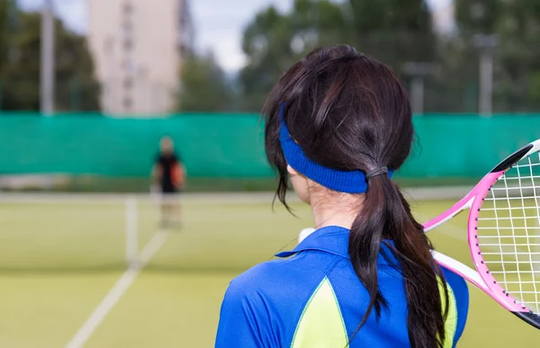 Zadní pohled ženy s tenisovou raketu na rameno na — Stock fotografie