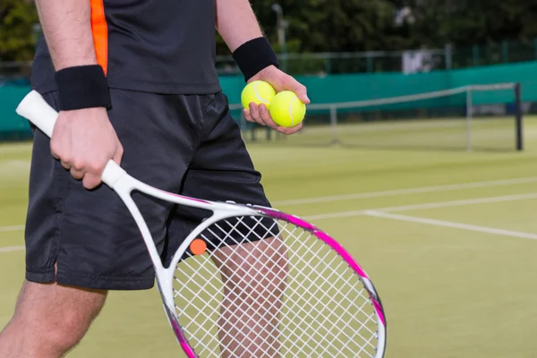 Крупный план человека, держащего теннисные мячи и ракетку — стоковое фото
