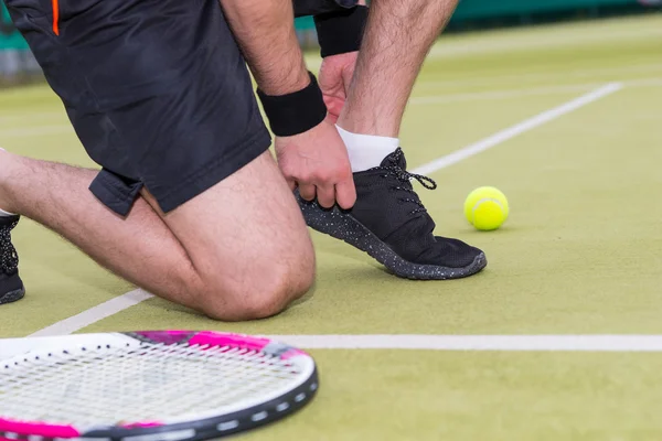 男子网球球员凑上绑鞋带左的球拍和球 — 图库照片