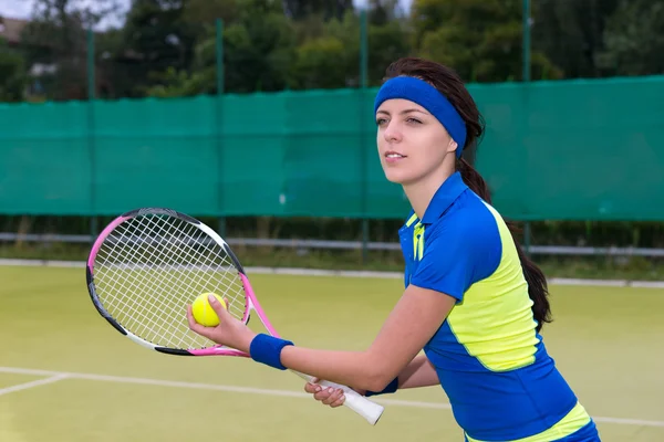 Hermosa joven jugadora de tenis sirviendo en el césped de tenis cou — Foto de Stock