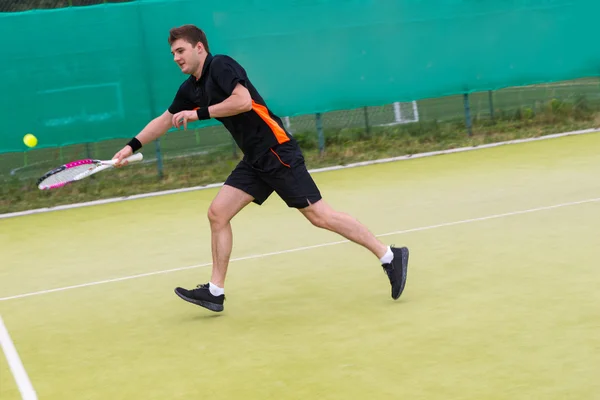 Junger Mann spielt am frühen Morgen Tennis auf dem Tennisplatz — Stockfoto