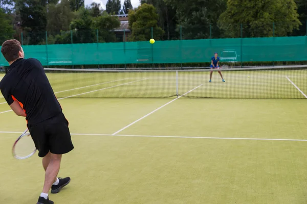 Молодой человек играет в теннис со своей партнершей — стоковое фото
