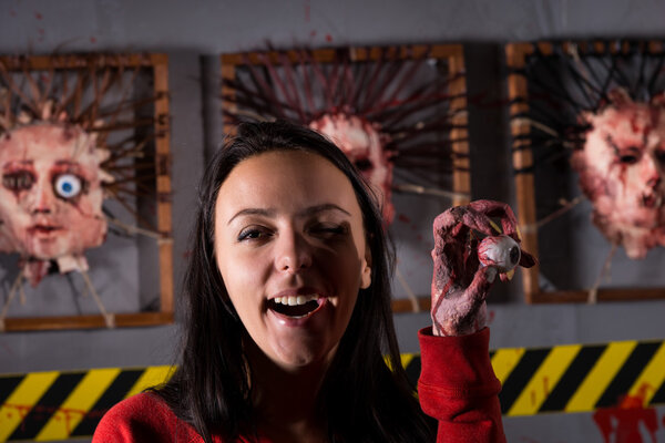 Смеющаяся молодая странная женщина, держащая глаза в морщинистой руке
