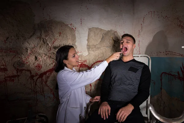 Сумасшедший ученый держит медицинское устройство перед пациентом в дю — стоковое фото
