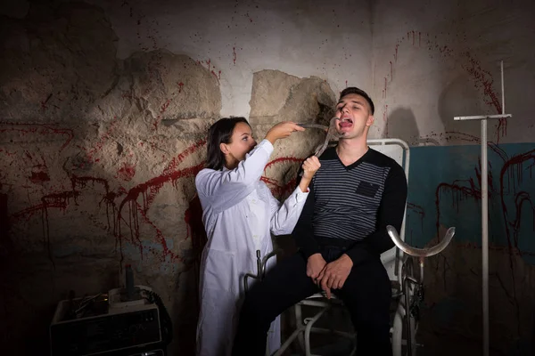 Cientista feminina segurando fórceps médicos na frente do paciente e — Fotografia de Stock