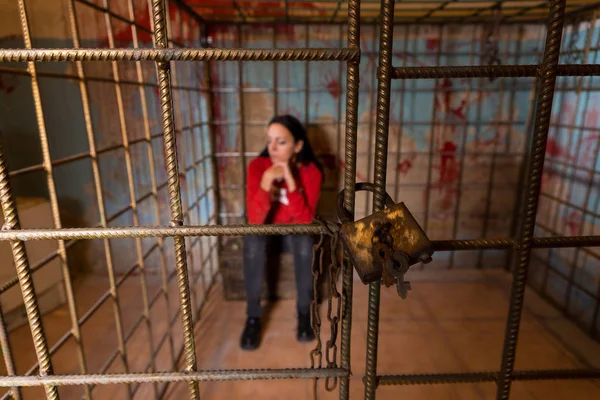 Vítima feminina presa em uma gaiola de metal com um sangue espalhado — Fotografia de Stock