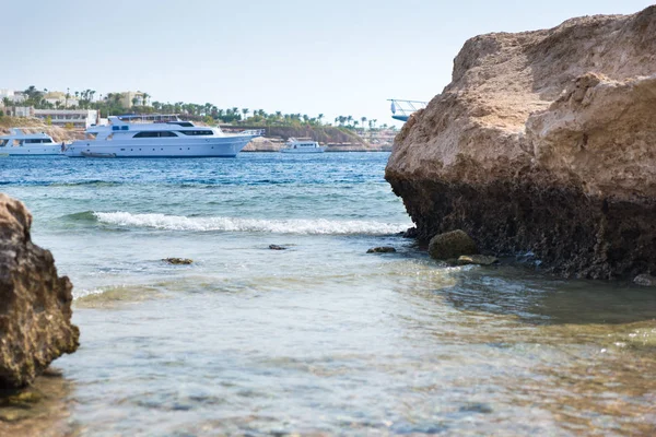 Вид на скалы и камни на пляже, яхта в море — стоковое фото