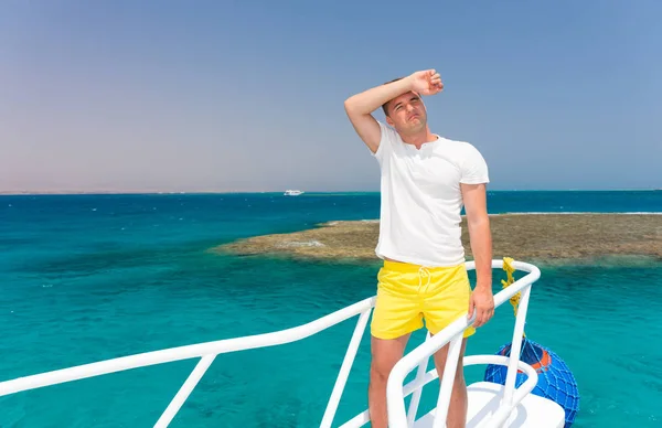 Красивый уставший мужчина стоит на яхте в солнечный летний день — стоковое фото