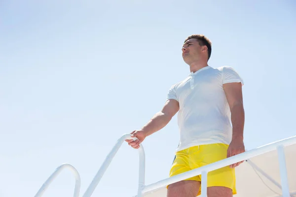 Красивый мужчина, стоящий на яхте и держащийся за перила — стоковое фото