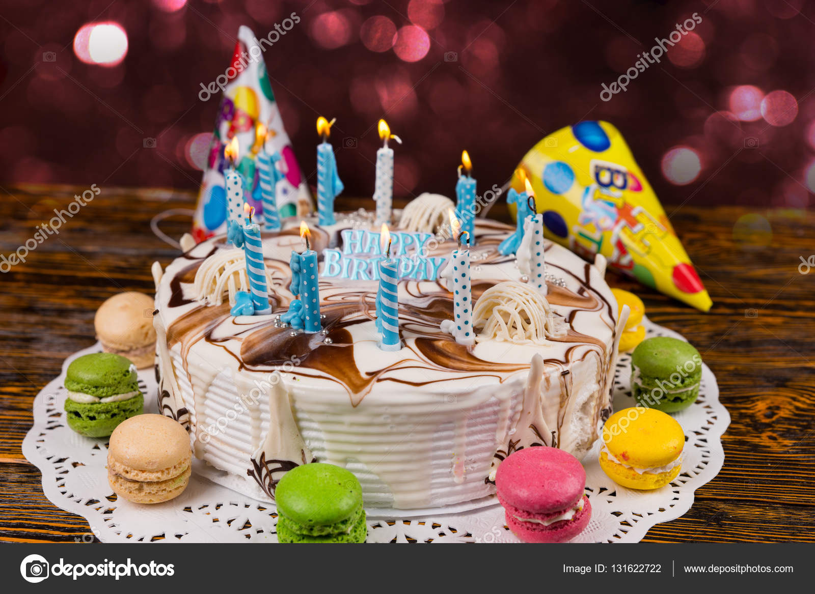 Torta di pleanno fatta in casa con un sacco di candele e Torta di pleanno fatta in casa con un sacco di candele accese sul tovagliolo bianco vicino macarons colorati differenti e tappi di vacanza sullo