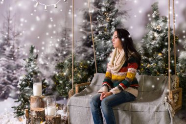 Bir tezgah veya bir salıncak karla kaplı bir parkta oturan genç kız 