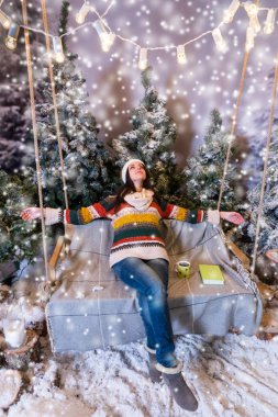 Neşeli genç kadın uzan salıncakta uzanmış kollarıyla 