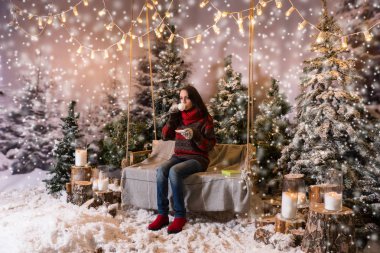 Flashlig altında bir battaniye ile bir salıncak üzerinde oturan genç kadın