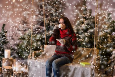 Bir battaniyenin altında el fenerleri ile bir salıncak üzerinde oturan kadın bir