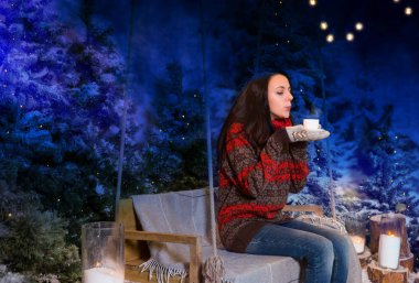 Flashlig altında bir battaniye ile bir salıncak üzerinde oturan genç kadın