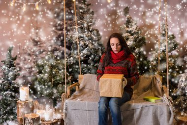 Bir battaniyenin altında el fenerleri ile bir salıncak üzerinde oturan kadın bir