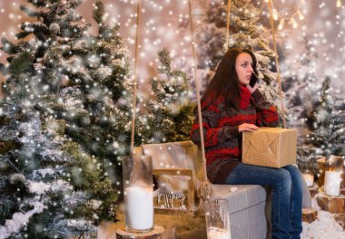 Bir hediye ile bir salıncak üzerinde oturan ve konuşurken genç kadın