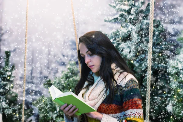 Jonge vrouw lezen van een boek tijdens de vergadering op een schommel met een blanco — Stockfoto