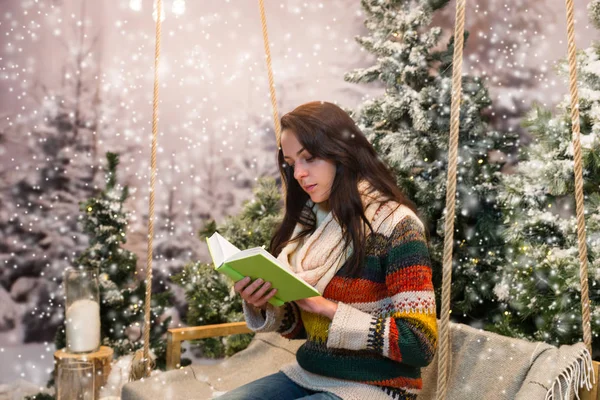 Mujer romántica leyendo un libro mientras está sentada en un columpio con un bl — Foto de Stock