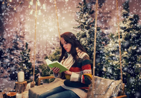 Hermosa mujer leyendo un libro mientras está sentado en un columpio con una b —  Fotos de Stock