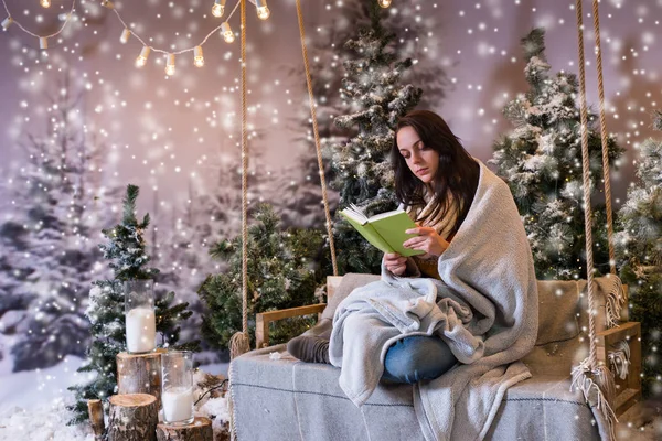 Mujer joven romántica leyendo un libro mientras está sentado en un columpio y — Foto de Stock