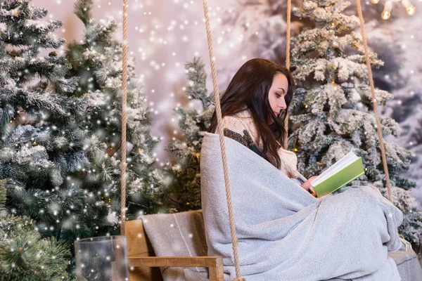 浪漫的女孩坐在一个秋千和 wrappe 同时阅读一本书 — 图库照片