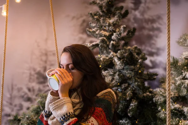 Mladá žena pít horký nápoj z hrnečku v zasněženém parku — Stock fotografie