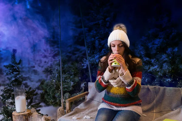 Beautiful young woman drinking hot drink in a snow-covered park, — Stock Photo, Image