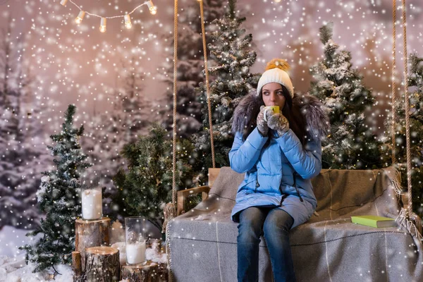 Donna in piumino blu bere bevanda calda mentre seduto su un — Foto Stock