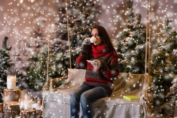 Bir battaniyenin altında el fenerleri ile bir salıncak üzerinde oturan kadın bir