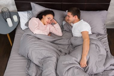 Yatakta yatan ve başucu t yakınındaki pijama giymiş genç Çift