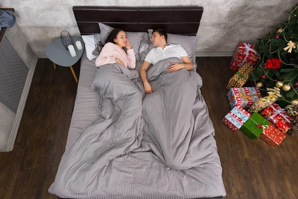 Pasangan muda berbaring di tempat tidur dekat meja samping tempat tidur dengan lilin di — Stok Foto