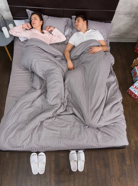 Mladý pár se probudit a ležící v posteli a nosí pyžamo — Stock fotografie