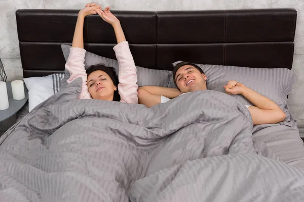 Giovane coppia assonnata svegliarsi e stretching mentre sdraiato in essere — Foto Stock