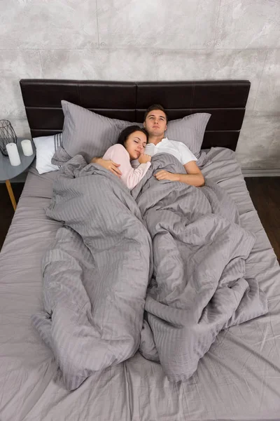 Young couple hugging each other while sleeping in the bed and we — Stock Photo, Image