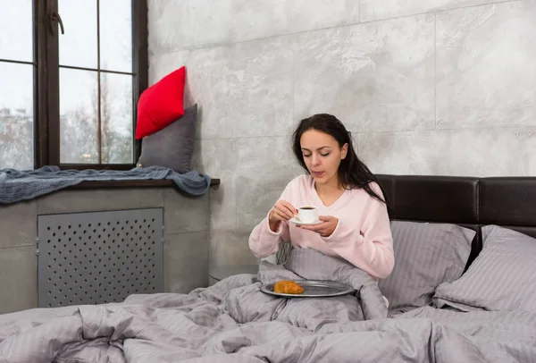 Mladá žena právě probudil, držící šálek kávy a s ní — Stock fotografie