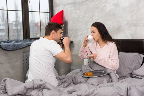 Ungt par vaknade precis, dricka en kopp kaffe och ha breakfas — Stockfoto