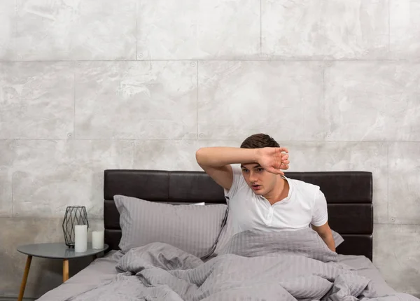 Terrified young man woke up from a nightmare and wiping sweat fr — Stock Photo, Image