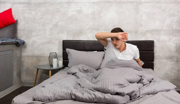 Terrified young man woke up from a nightmare and wiping sweat fr — Stock Photo, Image